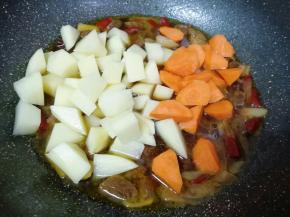  牛肉炖好以后下入土豆和胡萝卜翻炒均匀。