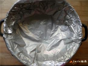 锡纸铺在石头上，周围贴近锅壁，一定要将锡纸延到锅外来，这样才不会滴水或滴糖到锅里（顶部多出的的部分包住锅的边沿）