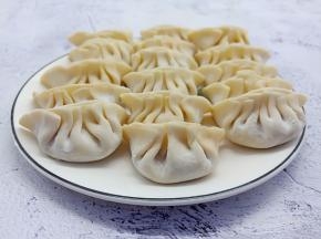 拿一个饺子皮、加肉末在饺子皮中间、依次包成褶子。