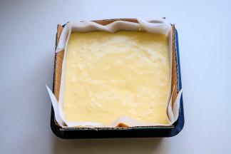 模具中提前铺好油纸，油纸要大一些，最好四周要比模具高出很多，把硬纸板放在油纸的外面，倒入拌匀的面糊，模具在台面上震几下，震出大气泡。