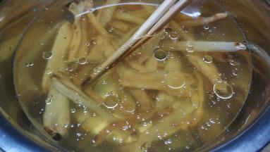 继续处理浸泡好的沙虫干：在盆里放入油和料酒（有助沙虫干更方便吐出沙子）
