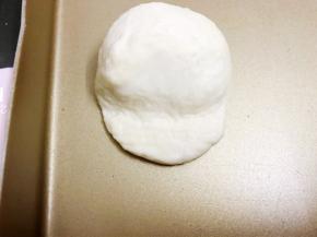 取稍微少点的那份面团滚圆后用刮板从中间压扁为头部
摆入那份大点的面团在压扁那里为脸部