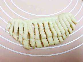 再取一份面团擀成椭圆形对折，用刮板切成小条，稍微扭一下