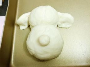 摆在头部两边，3克的面团摆在脸部中间