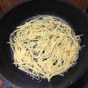 平底锅刷油，倒入土豆丝，用筷子摊匀，中小火煎制。