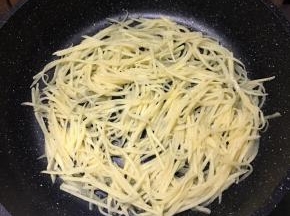 平底锅刷油，倒入土豆丝，用筷子摊匀，中小火煎制。