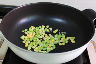 锅中留有的少许油，倒入玉米粒、青豆粒，煸炒熟，炒熟的青豆颜色更加翠绿。