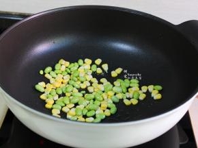 锅中留有的少许油，倒入玉米粒、青豆粒，煸炒熟，炒熟的青豆颜色更加翠绿。