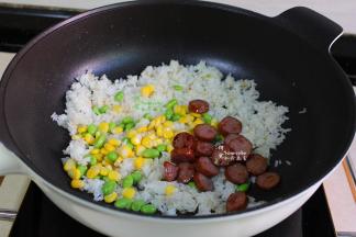 加入炒好的黑椒牛肉肠、青豆粒、玉米粒，一起大火翻炒，炒至米饭粒粒分明。