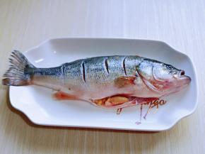 首先鲈鱼去鳞，去鳃，取出内脏，洗干净，鱼身体两面用刀划几道，不要太深，放入盘中。