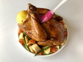 烘烤结束的提示音响起后，戴好防烫手套拿出烤好的鸡，撕掉锡纸，放在烤盘中间，将炒好的蔬菜均匀的铺在烤鸡周围，刷上一层蜜汁酱。