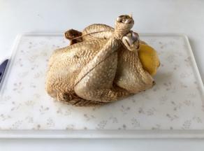 取一段棉绳放在鸡身下，鸡胸朝上，绕过鸡翅再把鸡腿捆住。（捆绑固定好的鸡会呈现一个球型，烤鸡端出来才会美美哒）