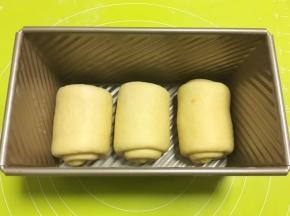 将卷好的面卷放入模具内，烤箱转至发酵键，放碗热水入烤箱二次发酵
