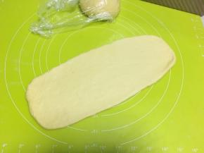 取一份松弛好的面团用擀面杖擀成长条，两边横着擀开，尽量将面团擀成长方形
