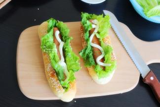 接着放入煎好的牛肉肠，再挤一些沙拉酱在牛肉肠上，热狗面包就做好了。