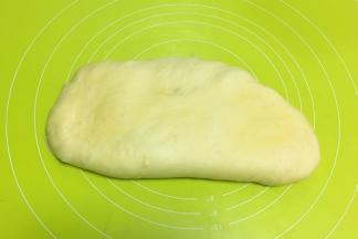 将面团倒在揉面垫上，按压排气
