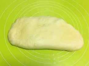 将面团倒在揉面垫上，按压排气
