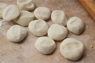 撒上面粉，用手掌按扁，边缘薄中间厚。这个粉活的饺子面团，擀的时候不会回缩，