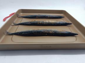 腌制好的秋刀鱼码在烤盘上。