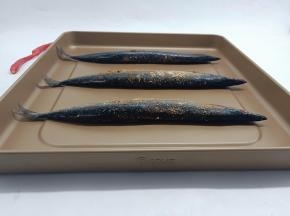 腌制好的秋刀鱼码在烤盘上。