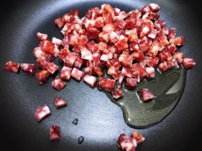 锅里加入花生油，倒入腊肠丁小火煸炒至透明出油