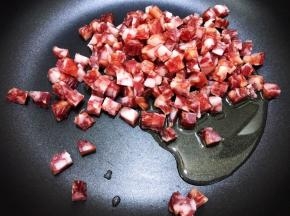 锅里加入花生油，倒入腊肠丁小火煸炒至透明出油