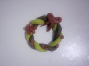 把蝴蝶结装饰在花环接口处，把其余的红色小圆点按自己喜欢装饰在花环饼干上，一个花环饼干就制作完成啦