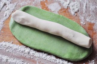 取绿色的菠菜面团搓长后略擀成长条状，然后刷上水，再放上搓成长条的白色面团。