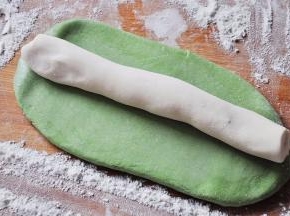 取绿色的菠菜面团搓长后略擀成长条状，然后刷上水，再放上搓成长条的白色面团。