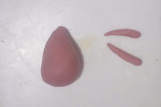 取一个小面团，分出1~2克再分成2等份搓长条制作小鹿的手臂如图，另一块搓成圆锥形制作小鹿的身体