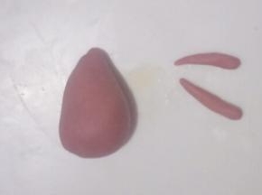 取一个小面团，分出1~2克再分成2等份搓长条制作小鹿的手臂如图，另一块搓成圆锥形制作小鹿的身体