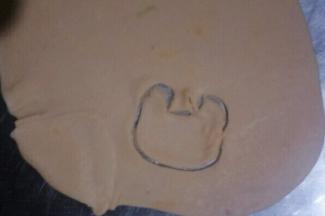 橙色面团擀成厚度为1mm把薄饼，切出如图形状制作小鹿的脸部