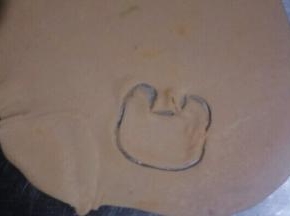 橙色面团擀成厚度为1mm把薄饼，切出如图形状制作小鹿的脸部