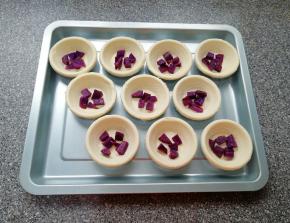 提前解冻的蛋挞皮摆在烤盘里，放上蒸好的紫薯。