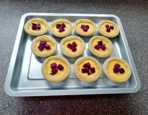 10分钟之后取出烤盘，蛋挞液呈半凝固状态，上面放上紫薯。