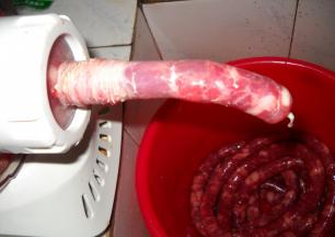 羊肠衣套在灌肠器上，启动面条机慢慢将肉灌入肠衣中。