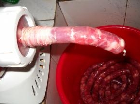 羊肠衣套在灌肠器上，启动面条机慢慢将肉灌入肠衣中。