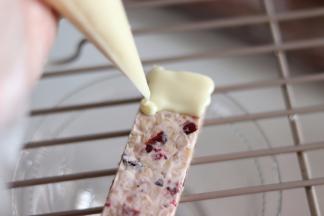 白、黑巧克力分别放入裱花带中，放到40-50度的热水中，融化成液态，剪口后淋到能量棒上。