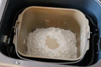 倒入面包粉，面包粉中间挖个洞，加入干酵母粉，选择和面程序开始揉面；