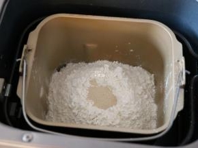 倒入面包粉，面包粉中间挖个洞，加入干酵母粉，选择和面程序开始揉面；