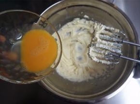 分两次加入全蛋液，每次都待搅打融合后再添加下一次，搅打至黄油蓬松发白。