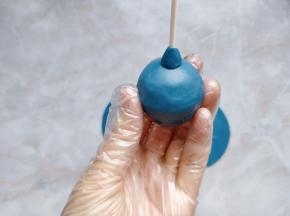 在圆球中心插入纸棒，取一小块翻糖皮捏成圆锥状，装饰在图中位置充当花心，也起到固定蛋糕芯的作用。