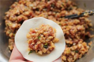 取一个饺子皮，放入一勺饺子馅。