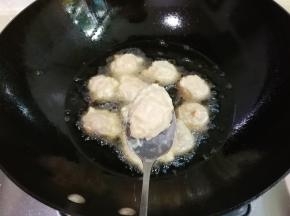 锅中放入一大碗豆油烧热，用勺子接住手中挤出的肉糊放入锅中