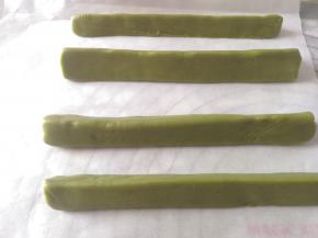 深色抹茶面团分成四份，一份稍小一点，待会儿作为圣诞树的顶部，其他三份分成差不多大借助油纸，大概整成三角形。