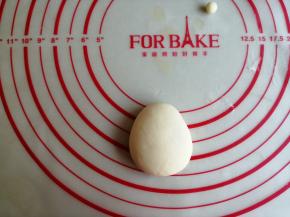 将白色小面团略压扁一下，弄成上面小，下面宽一点，如图