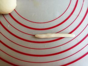 在备用的白色团里，揪出2克面团，搓成长条状