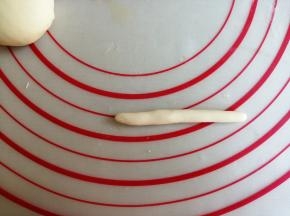 在备用的白色团里，揪出2克面团，搓成长条状