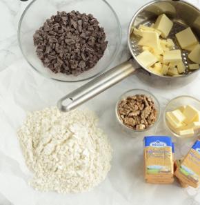 核桃仁120度(实际温度150度，我烤箱偏高30度左右)烘烤10分钟，切碎，晾凉备用，巧克力切小块，备用。黄油切小块，145g倒入锅中，剩下55g放一旁备用。苏打粉+泡打粉+盐+中筋面粉混合，过筛两遍，放一旁备用。