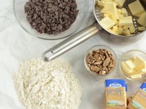 核桃仁120度(实际温度150度，我烤箱偏高30度左右)烘烤10分钟，切碎，晾凉备用，巧克力切小块，备用。黄油切小块，145g倒入锅中，剩下55g放一旁备用。苏打粉+泡打粉+盐+中筋面粉混合，过筛两遍，放一旁备用。